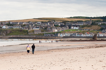 Elderly couple walking together on Cullen Beach in Morayshire, Scotland