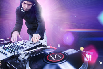 Club DJ playing mixing music on vinyl turntable at party from nightlife lights