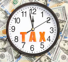 Time to taxes. Clock with word "TAX" on dollars background. Busi