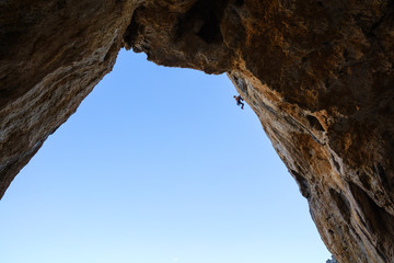 Young man climbing in cave, Telendos Island, Greece 