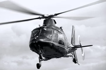 Fotobehang Black and white image of a helicopter hovering in flight © Tony Baggett