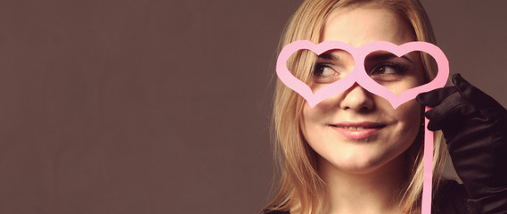 Beautiful girl with paper glasses in the shape of hearts