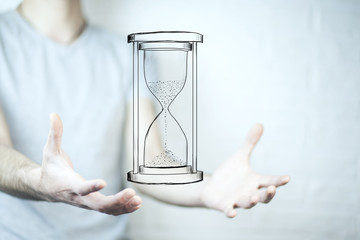 Man's hand holding hourglass sand