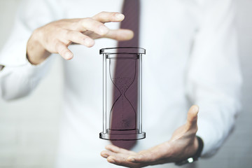 Man's hand holding hourglass sand