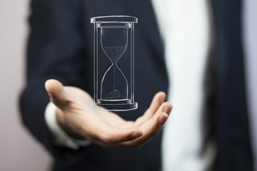 Man's hand holding hourglass sand