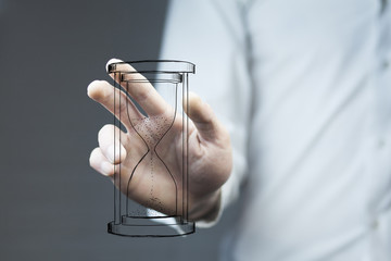 Man's hand holding hourglass sand