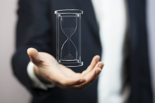 Man's hand holding hourglass sand