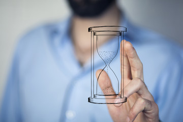 Man's hand holding hourglass sand