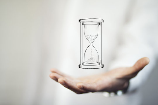 Man's hand holding hourglass sand