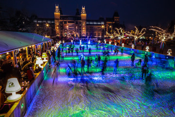 Naklejka premium Amsterdam, Holandia - 12 stycznia 2017 r .: Wiele osób jeździ na łyżwach na zimowym lodowisku w nocy przed Rijksmuseum, popularnym miejscem turystycznym w Amsterdamie, Holandia.