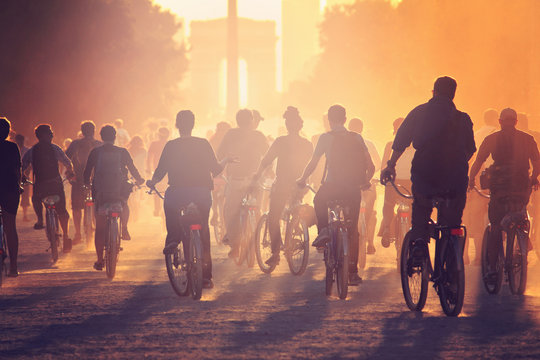 Silhouettes of people on bicycles on the sunset in the city park