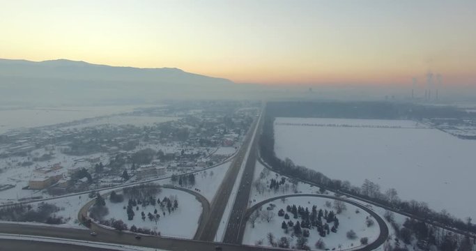 
 Aerial shot of a highway road with traffic cars and trucks on the road junction in winter.