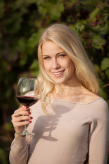 Woman drinks red wine in vineyard