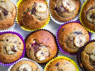 Homemade muffins in bright paper decorated with banana and chocolate. Top view, flat lay