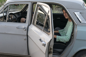 boy peeps out of an old car. Two young boys in the car. Company teenagers. journey together. fun pastime.