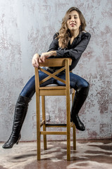 Fototapeta na wymiar Young girl with curly hair in a black shirt, jeans and high boots cowboy western style 