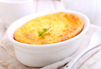 Cottage cheese casserole in white dish decorated with mint, on a white wooden background. Selective focus.