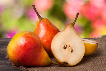 two whole and half of pear on a wooden table with cloth burlap
