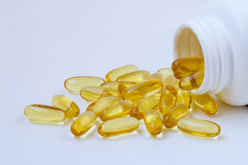 Fish oil, omega 3 and vitamin D capsules in a plastic bottle.