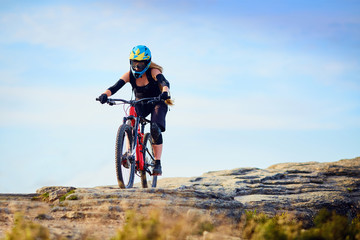 Obraz premium Female MTB biker, riding downhill on rocks