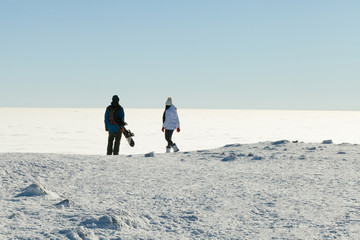 Snowboarder and his girlfrined looking at landscape from the top of a mountain
