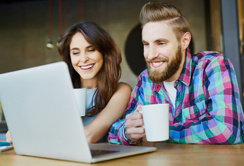 Happy couple looking while drinking coffee in cafe