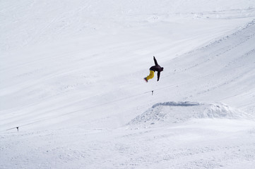 Snowboarder jumping in snow park at ski resort on sun winter day