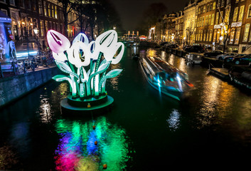 AMSTERDAM, NETHERLANDS - JANUARY 11, 2017: Cruise boats rush in night canals. Light installations on night canals of Amsterdam within Light Festival. January 11, 2017 in Amsterdam - Netherland..