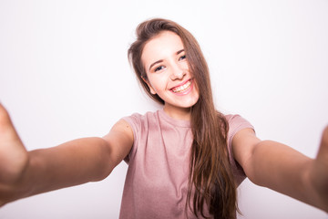 Fototapeta na wymiar Young happy smile girl take selfie on white background