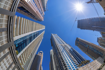 Fototapeta na wymiar Skyscrapers against sunshine by fisheye in Dubai, United Arab Emirates