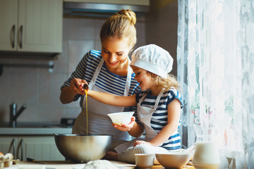 happy family in kitchen. mother and child preparing dough, bake