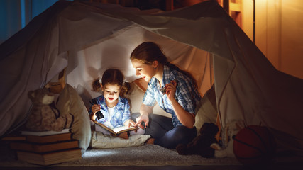mother and child daughter with a book and a flashlight before go - obrazy, fototapety, plakaty