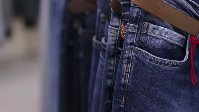 Close up of many blue jeans hanging on a rail