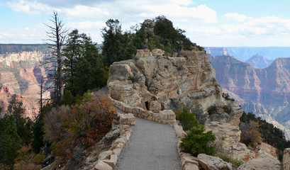 Path to bright angel vista point in Grand Canyon National Park landscape from north rim on a cloudy sky