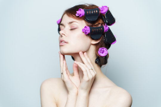a woman winds hair on curlers, closed eyes, a hairdo