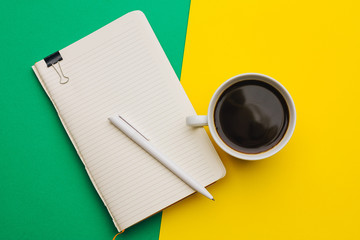 notebook pen and cup of coffee on a bright background