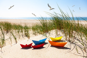 Papierschiff im Dünengras am Strand