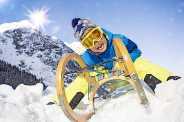 Junge in den Alpen mit Schlitten