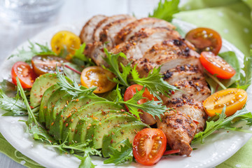 Healthy salad plate with colorful tomatoes, chicken breast and avocado