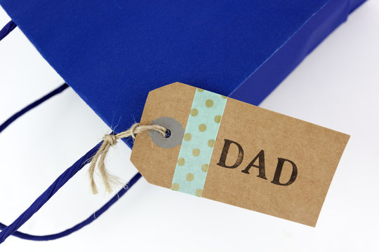 Close Up Of Father's Day DAD Tag Attached To Gift Bag. Isolated.