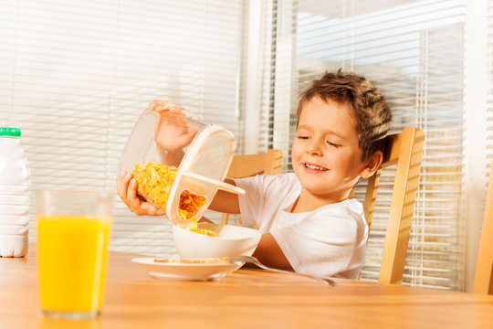 Little boy pouring corn flakes making breakfast
