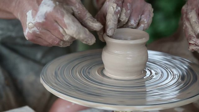 Man and woman makes a pot on pottery wheel. Hands of a potter and his apprentice. Woman is the pupil of a potter. Man and woman hands close up