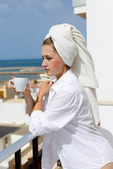 Relaxing attractive woman in bed over sunny ocean outdoors background.