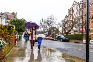 People walk in winter rain in London subrub