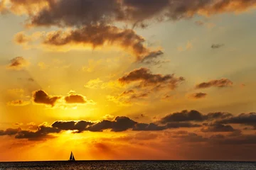 Foto op Plexiglas Seven Mile Beach, Grand Cayman Zeilboot aan de horizon passeert voor de ondergaande zon op Seven Mile Beach, Kaaimaneilanden
