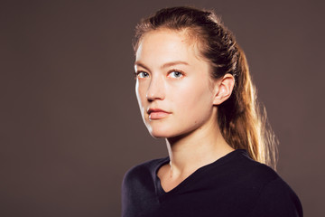 Young caucasian woman in three quarters profile looks at viewer with a neutral expression