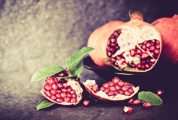 Fresh red pomegranate and seed  with leaves over black stone 