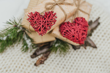 The Valentines day concept. Valentines gifts, vintage romantic red heart gifts boxes, tree branches and bark of tree lie on a woolen blanket background. Winter theme. Top view. Free space.