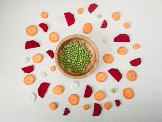Background from cut beet,carrot,peas,onion.Wooden plate.Top view