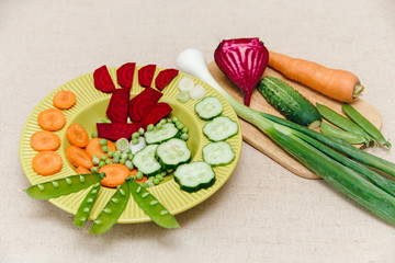 Fresh beet,carrot,green onion,peas on the plate,tablecloth and board.Vitamin vegetable.Healthy organic food.